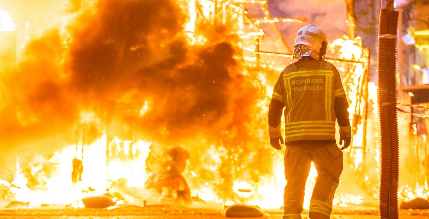 Silhouette of fireman trying to control a fire in a street during a night.