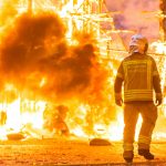 Silhouette of fireman trying to control a fire in a street during a night.