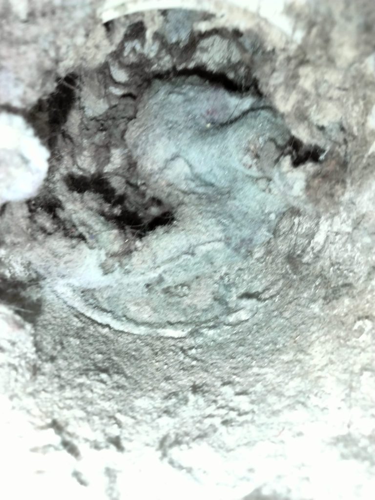 Clogged dryer vent filled with lint and debris before dryer vent cleaning service.