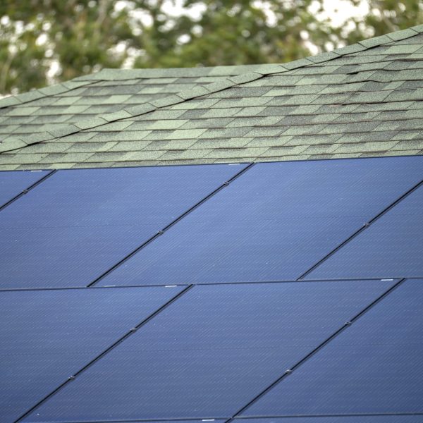 Aerial view of typical american building roof with blue solar photovoltaic panels for producing clean ecological electric energy. Investing in renewable electricity for retirement income concept.